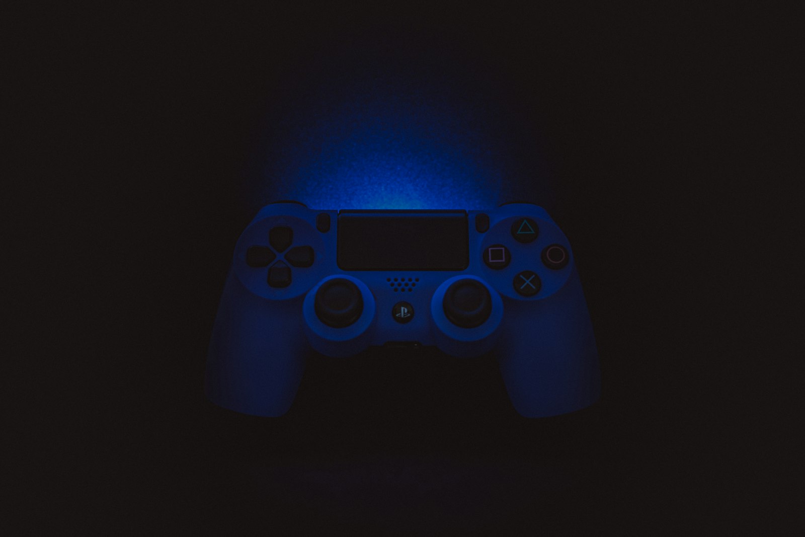 A game controller glowing blue in the dark